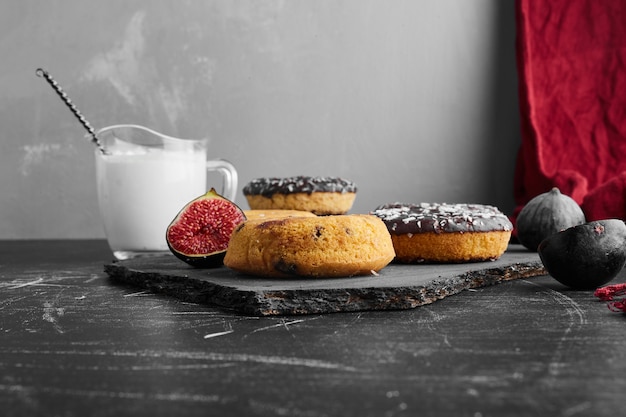 Ciambelle al cioccolato su una superficie nera su una tavola di pietra.