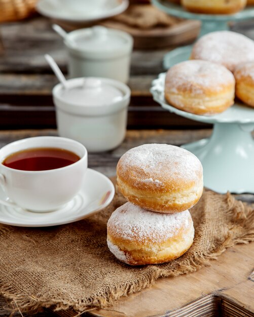 Ciambelle di crema pasticcera zuccherate in polvere e tè nero