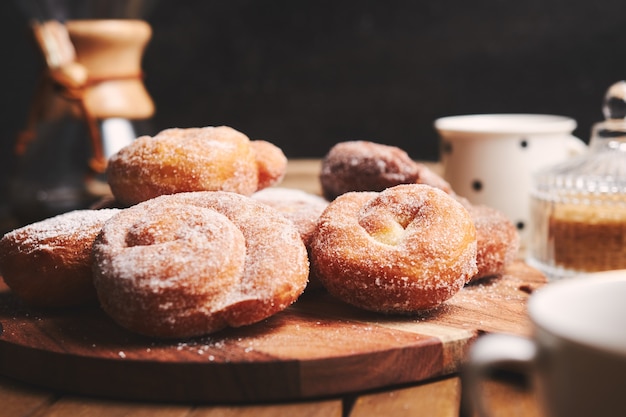 Ciambelle di serpente con zucchero a velo e caffè chemex su un tavolo di legno