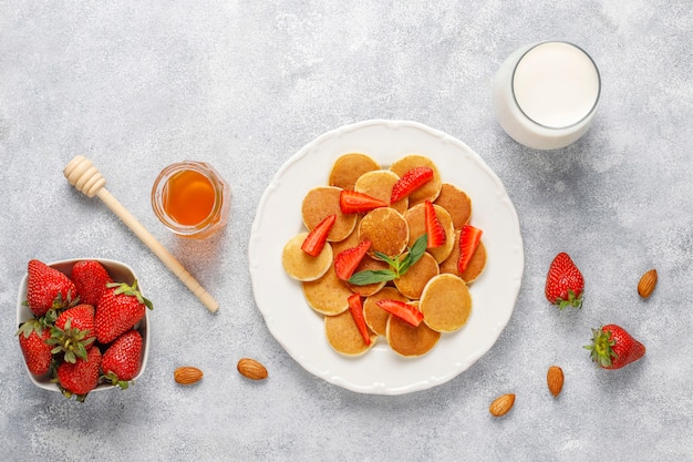 Cibo alla moda - cereali mini pancake. Mucchio di frittelle di cereali con frutti di bosco e noci.