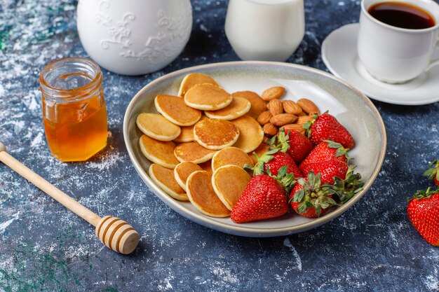 Cibo alla moda - cereali mini pancake. Mucchio di frittelle di cereali con frutti di bosco e noci.