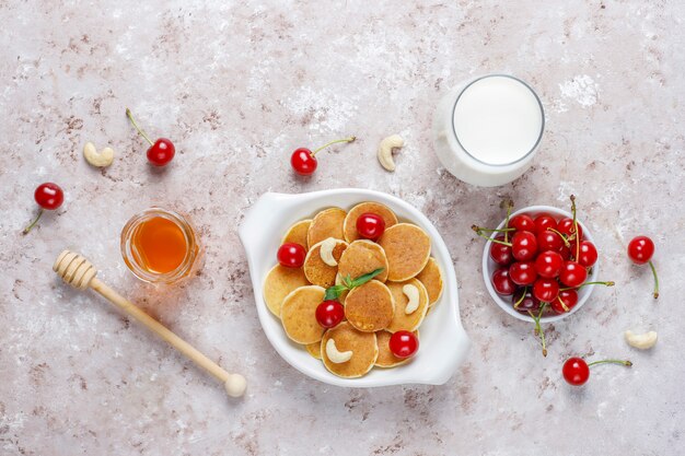 Cibo alla moda - cereali mini pancake. Mucchio di frittelle di cereali con frutti di bosco e noci.