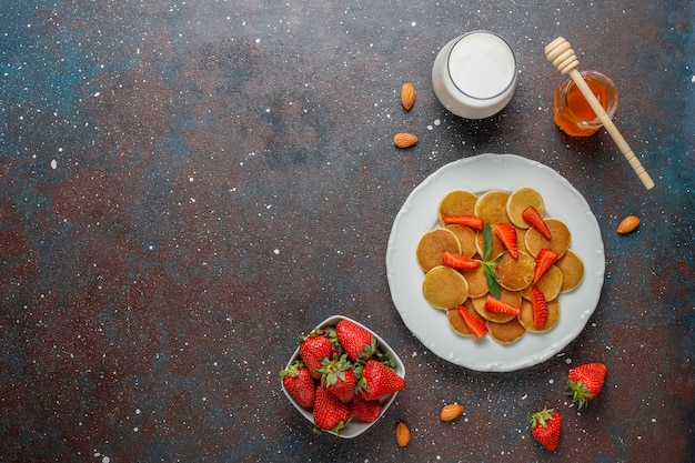 Cibo alla moda - cereali mini pancake. Mucchio di frittelle di cereali con frutti di bosco e noci.