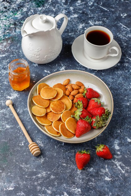 Cibo alla moda - cereali mini pancake. Mucchio di frittelle di cereali con frutti di bosco e noci.