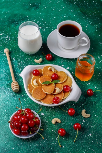 Cibo alla moda - cereali mini pancake. Mucchio di frittelle di cereali con frutti di bosco e noci.