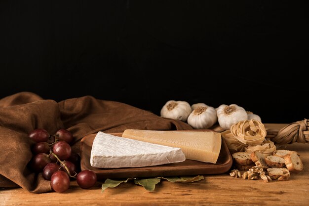 Cibo fresco con aglio, formaggio e uva vicino panno marrone sul tavolo