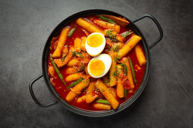 Cibo tradizionale coreano di formaggio Tokbokki su priorità bassa nera del bordo. Piatto da pranzo.