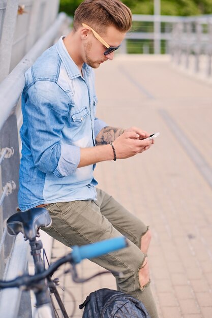 Ciclista che utilizza uno smartphone su un ponte d'acciaio.