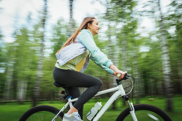 Ciclista della ragazza felice che guida su una mountain bike fuori. Viaggio avventuroso.