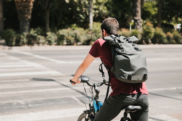 Ciclista di vista posteriore che aspetta al passaggio pedonale