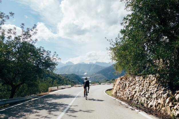 Ciclista in sella a una bicicletta al tramonto in una strada di montagna