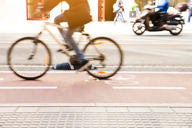 Ciclista irriconoscibile in sella a una bicicletta su una pista ciclabile attraverso la strada cittadina