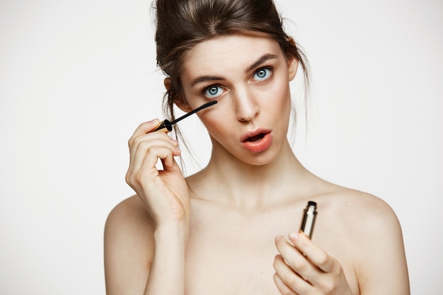 Ciglia di tintura bella ragazza divertente con la bocca aperta guardando la telecamera su sfondo bianco. Concetto di salute e cosmetologia di bellezza.