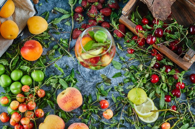 Ciliege fresche rosse sulla scatola di legno con un bicchiere di succo di frutta e frutta fresca