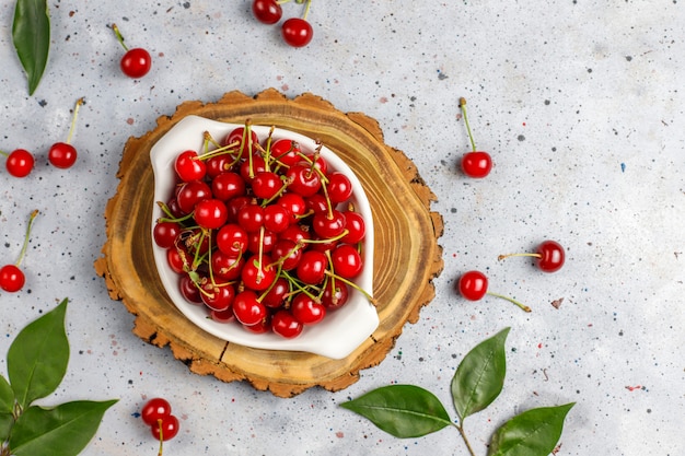 Ciliege rosse in ciotola del piatto sulla tavola grigia