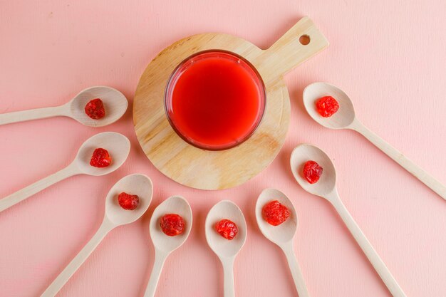 Ciliege secche con succo in cucchiai di legno sul tavolo rosa e tagliere