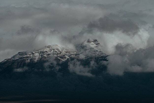 Cime innevate delle montagne coperte dal cielo nuvoloso scuro