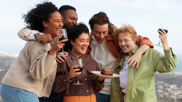 Cinque amici che bevono vino e posano durante la festa all'aperto