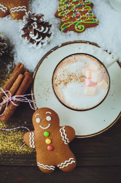 Cioccolata calda o bevanda al cacao con biscotto uomo di pan di zenzero e cannella su sfondo tavolo in legno vintage snowon