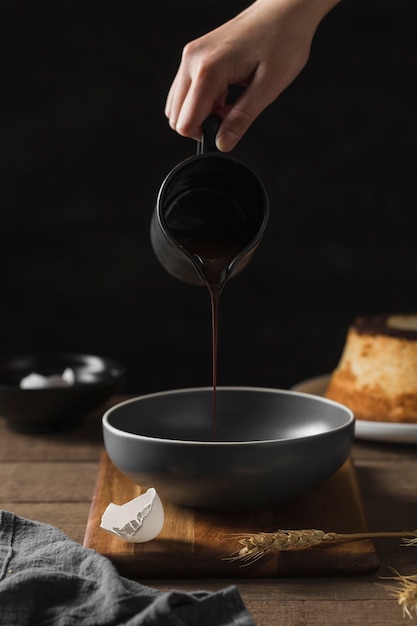 Cioccolato di versamento della mano del primo piano nella pentola