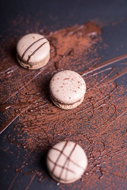 Cioccolato in polvere e sciroppo sopra i macarons su sfondo nero