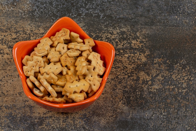 Ciotola arancione di cracker su marmo.