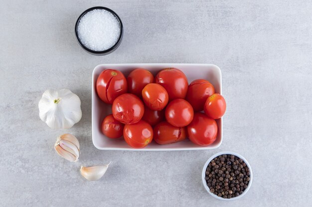 Ciotola bianca di pomodori in salamoia posti sulla superficie della pietra.