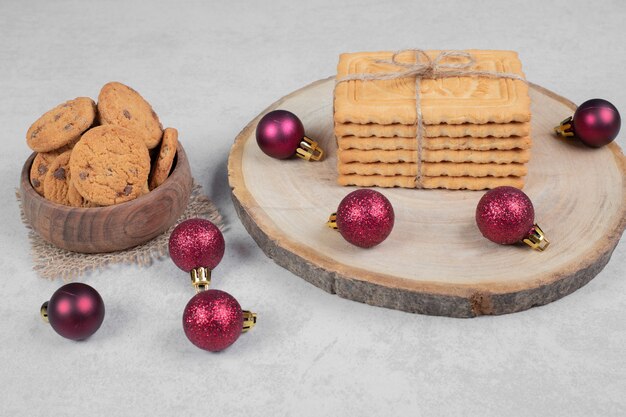 Ciotola di biscotti con patatine fritte, biscotti e palle di Natale sul tavolo bianco. Foto di alta qualità