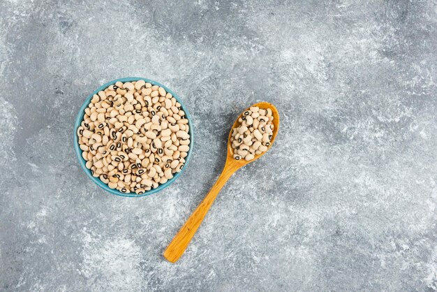 Ciotola di fagioli bianchi con cucchiaio sul tavolo di marmo.