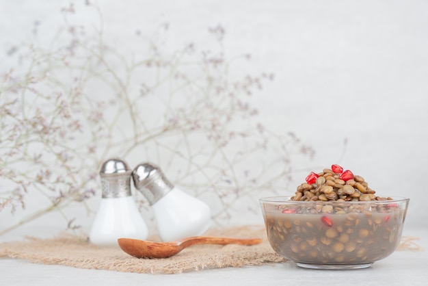 Ciotola di fagioli con semi di melograno sul tavolo bianco