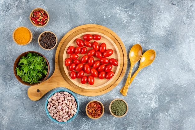 Ciotola di fagioli crudi, pomodori e spezie su sfondo marmo.