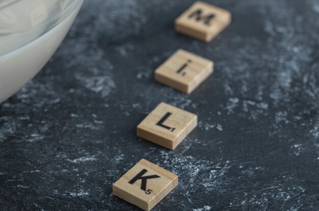 Ciotola di latte e lettere di legno scritte come latte.