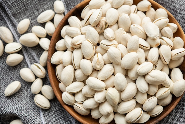 Ciotola di legno con pistacchi di noci. su uno sfondo di legno, vicino a una borsa di tela da imballaggio. Cibo sano e spuntino, cibo vegetariano biologico.