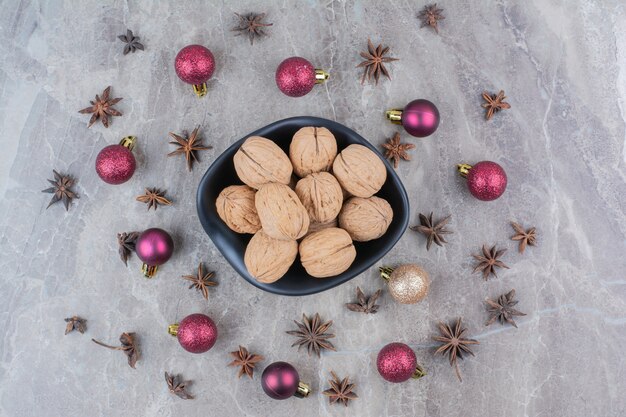 Ciotola di noci con chiodi di garofano e palline di Natale.