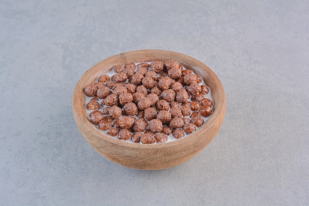 Ciotola di palline di cereali al cioccolato con latte sul tavolo di pietra.