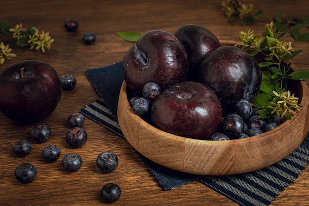 Ciotola fresca sana piena di prugne e mirtilli