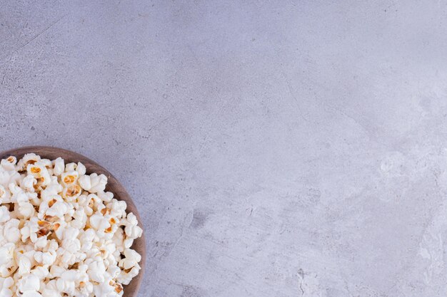 Ciotola in legno piena di popcorn croccanti su fondo marmo. Foto di alta qualità