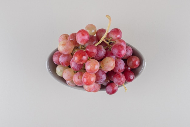 Ciotola piccola con grappolo d'uva su marmo