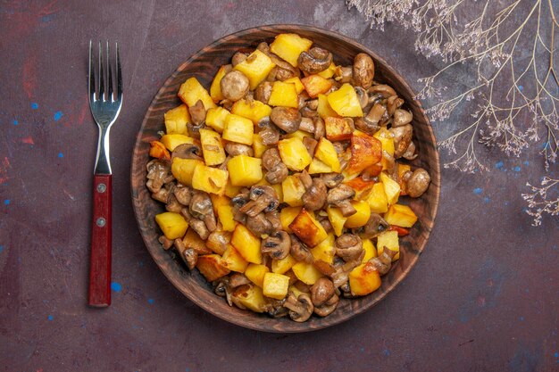 Ciotola vista dall'alto con cibo e forchetta una forchetta e un piatto con patate e funghi sono sul tavolo
