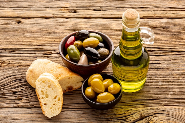 Ciotole di olive ad alto angolo fette di pane e bottiglie di olio