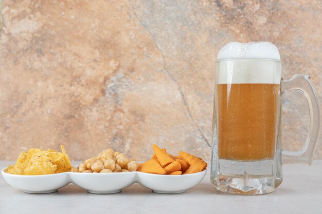 Ciotole per snack e bicchiere di birra sul tavolo di pietra.