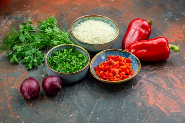 Ciotole vista dal basso con peperoni rossi tritati e verdure riso prezzemolo cipolle rosse peperoni rossi sul tavolo rosso scuro