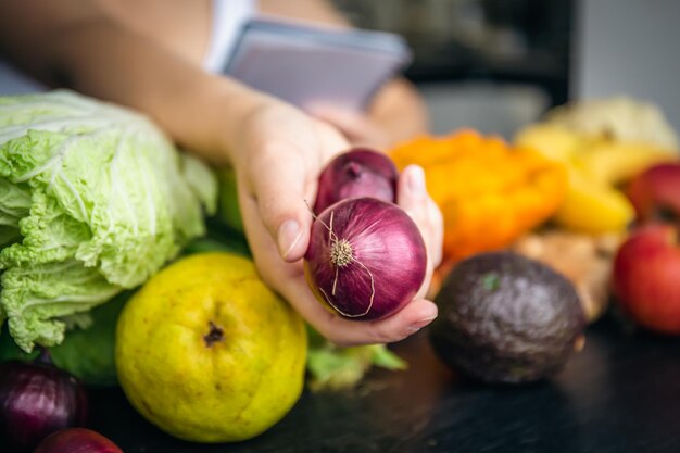 Cipolla del primo piano in mani femminili su uno sfondo sfocato della cucina