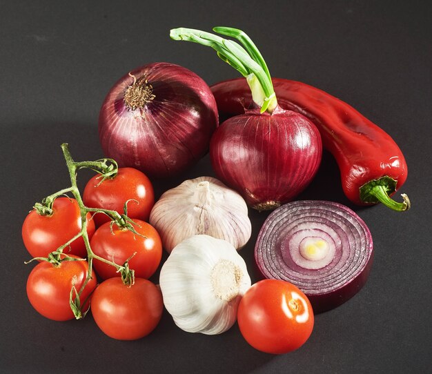 Cipolla e aglio e peperoncini e pomodori isolati su un nero.