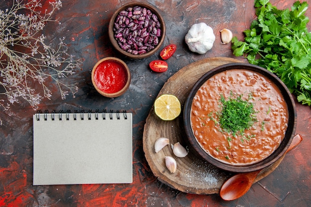 Classico pomodoro sapone fagioli aglio cucchiaio bottiglia di olio limone ketchup e taccuino sulla tavola di colori misti