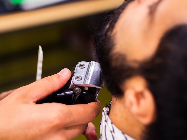 Cliente del primo piano che ottiene la barba tagliata