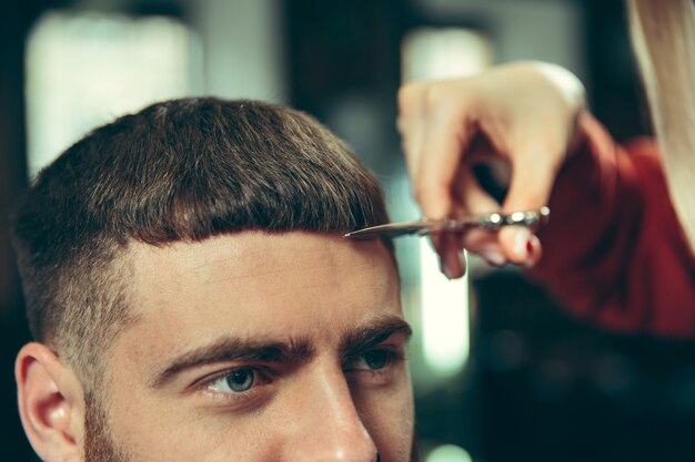 Cliente durante la rasatura della barba nel negozio di barbiere. Barbiere femminile al salone. Parità dei sessi. Donna nella professione maschile.