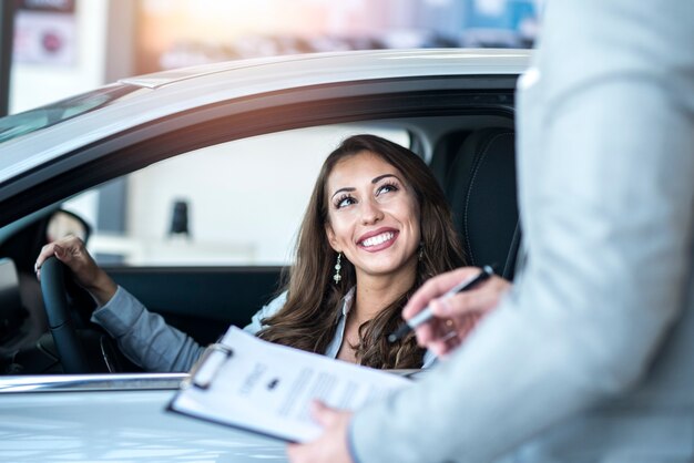 Cliente felice che acquista un'auto nuova di zecca presso un concessionario di automobili locale