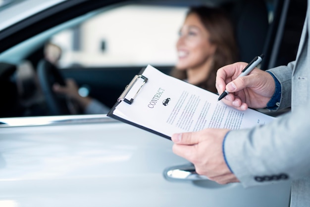 Cliente felice che acquista un'auto nuova di zecca presso un concessionario di automobili locale