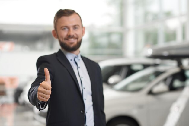 Cliente felice che posa nella concessionaria di automobili